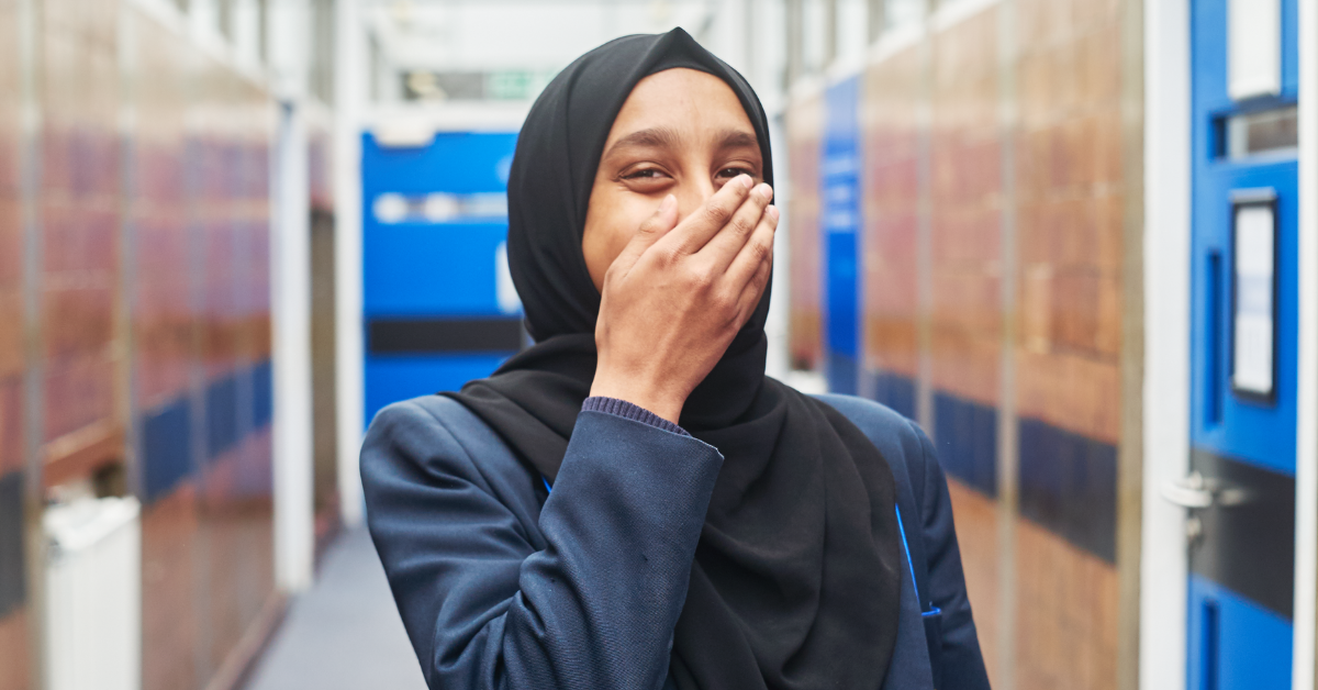 Image of a young woman covering her mouth looking happy Image of a young woman covering her mouth looking happy