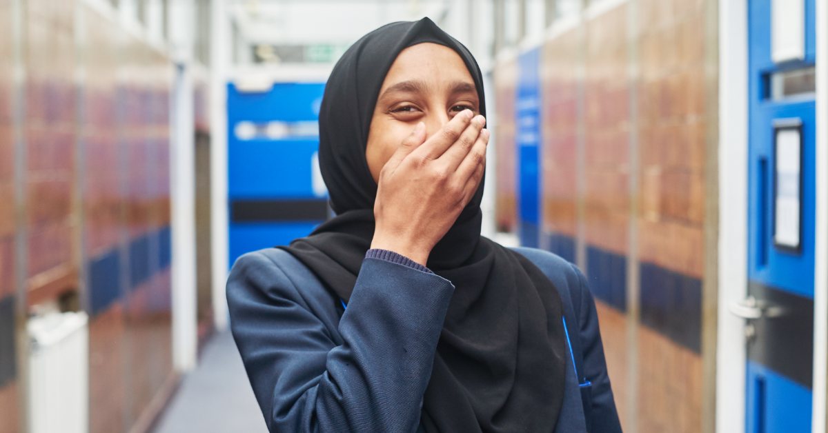 Image of a young woman covering her mouth looking happy